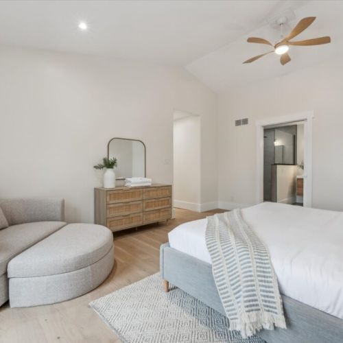 Retreat to a beautifully furnished bedroom featuring a lounge chair, ceiling fan, and soft linens for a peaceful night's sleep.