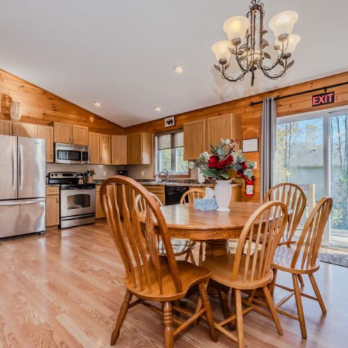 The spacious kitchen and dining area is perfect for family gatherings, featuring modern stainless steel appliances and ample counter space for preparing meals. The dining table seats six comfortably, with plenty of natural light flowing in through the patio doors that lead to the back deck, ideal for BBQs or enjoying outdoor meals.