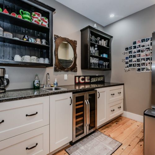 Elegant kitchenette featuring open shelving with glassware, a sleek countertop with a small sink, and a vintage mirror—perfect for a stylish and functional space.