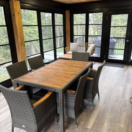 This expansive covered deck is perfect for outdoor dining, featuring comfortable seating and surrounded by beautiful forest views.