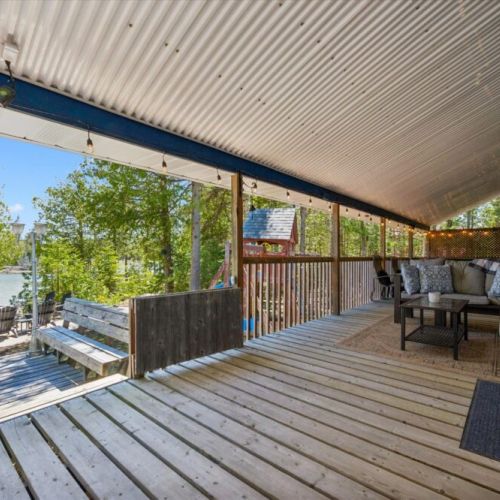 Expansive covered deck with comfortable lounge seating and peaceful waterfront views just steps away.