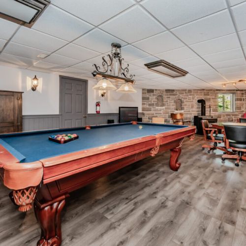 🎯 **Game Night Paradise**  
Enjoy unforgettable evenings in this spacious game room, complete with a billiards table, poker setup, cozy seating, and rustic ambiance—perfect for your family getaway or group retreat.