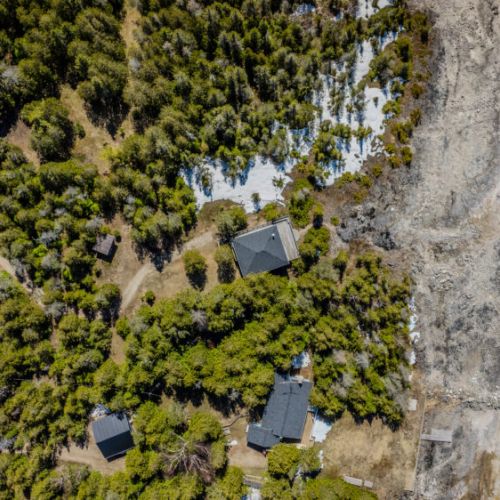 Aerial view of private cottage lot surrounded by forest and steps from the shoreline — the perfect secluded lakefront vacation escape.