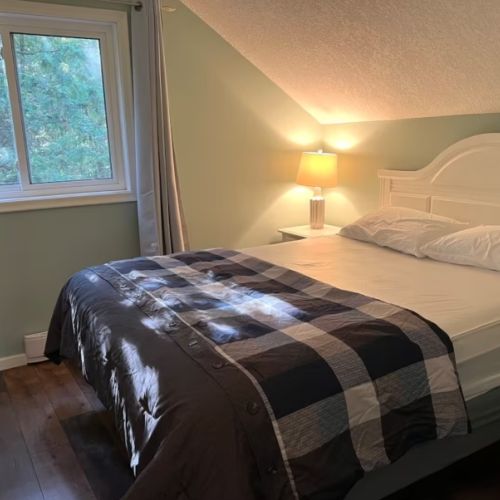 Wake up to sunlight streaming through the trees in this tranquil upstairs bedroom, complete with fresh linens and calming decor.