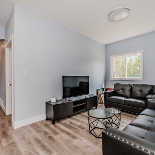 This cozy entertainment room features a comfortable sofa, a large TV, and modern decor. It's an ideal space for watching movies, playing games, or simply relaxing