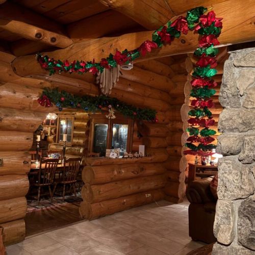 Fireside lodge glows with garlands arching over hand hewn logs and stone for a true winter cabin welcome