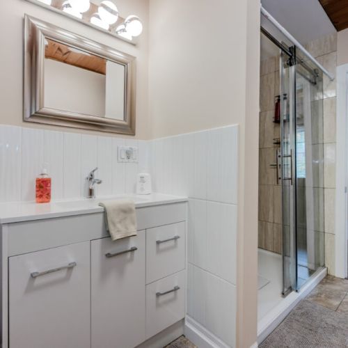 A modern bathroom featuring a sleek vanity, a glass-enclosed shower, and clean, contemporary decor. A perfect space to refresh during your stay.