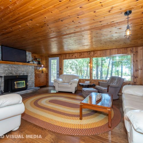Large, inviting living room with big windows, comfy seating, and a stunning stone fireplace.