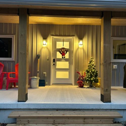 A warm winter welcome—glowing lights, fresh snow, and holiday charm at the cottage door