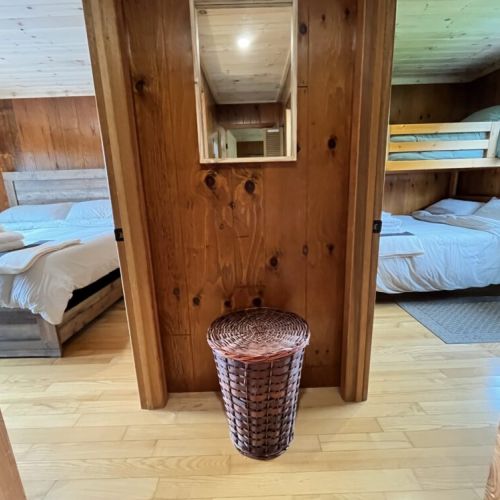A hallway view leading to the two adjacent bedrooms, showcasing the rustic wood interior and cozy sleeping arrangements.