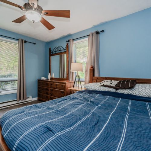 The master bedroom is bright and airy, featuring a large bed and windows with views of the surrounding greenery for a peaceful retreat.