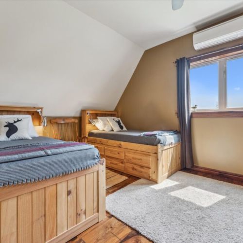 Charming upstairs twin room with two single beds and nature-themed accents—great for kids or friends.