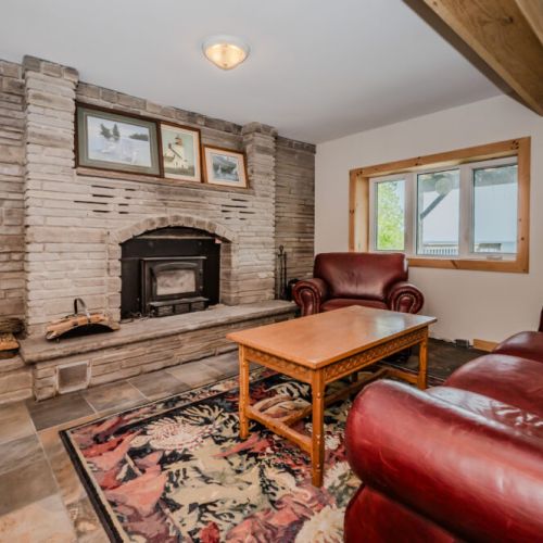 Relax in the comfort of this inviting living room, featuring a charming stone fireplace and plush leather seating, ideal for unwinding after a day of outdoor fun.