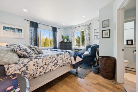 Wake up to sunshine and nature in this spacious bedroom, complete with comfortable seating and large windows overlooking the property.