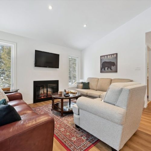 Bright and inviting living space with vaulted ceilings, large windows, and a cozy fireplace for relaxing after a day of exploring.