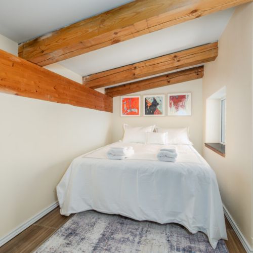 A cozy bedroom with exposed wood beams creates a peaceful retreat for a restful night's sleep.