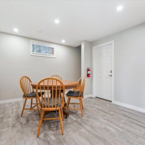 Cozy lower-level games nook with a round table, four wooden chairs, and a shelf stocked with classic board games—perfect for family fun or rainy-day entertainment.