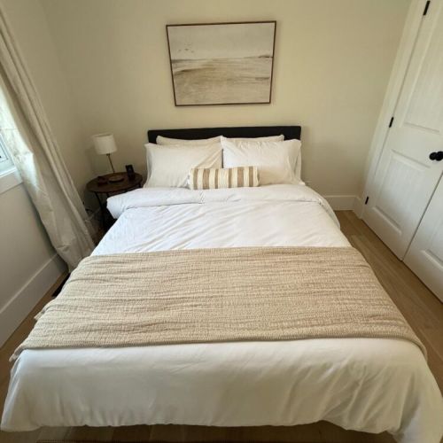 Unwind in this cozy, light-filled bedroom with soft linens and neutral tones—a restful haven after a day of exploring.