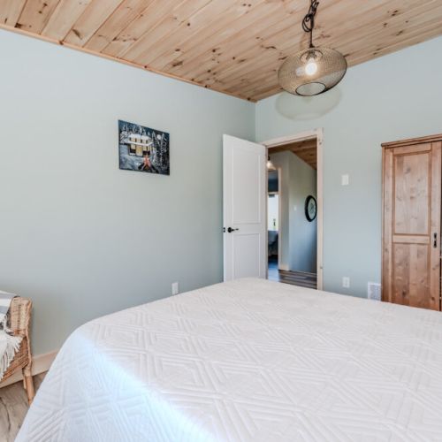 Unwind in a peaceful bedroom featuring wood accents, soft lighting, and cottage-style furnishings—a restful escape in every season