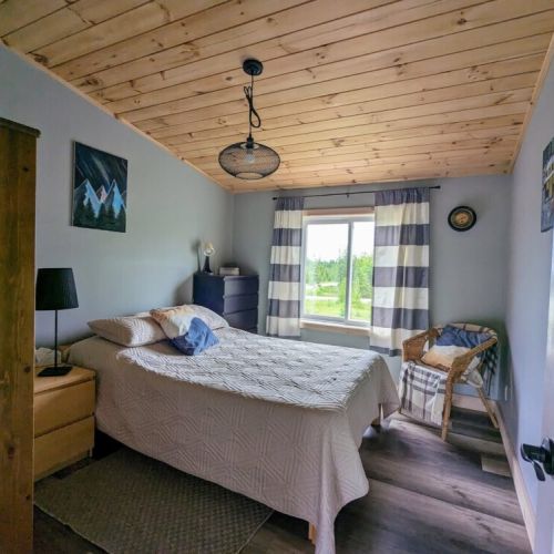 Charming third bedroom with wood-paneled ceiling, natural light, and a relaxed cottage feel for a great night’s sleep.