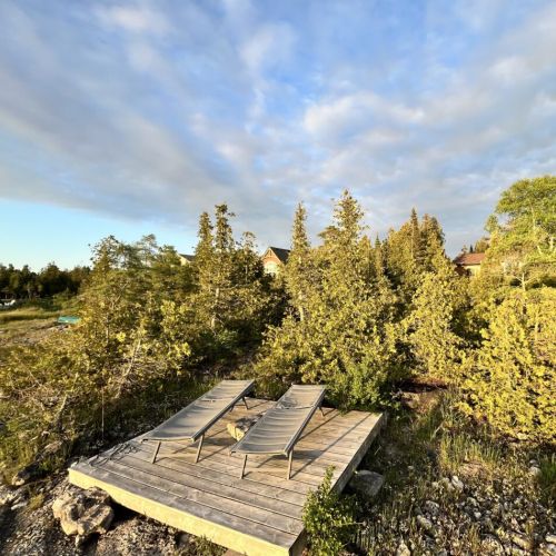 Enjoy alfresco dining at the picnic table by the firepit, with the calming sounds of the water and the gentle breeze creating a perfect outdoor dining experience.