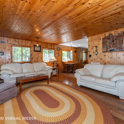 Open-concept living room with plenty of comfortable seating, big windows, and classic cottage décor.
