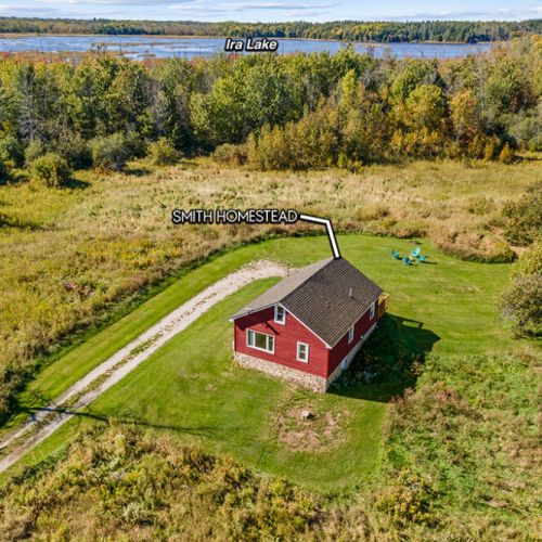 Smith Homestead sits surrounded by nature, with beautiful Ira Lake visible beyond the nearby forest.