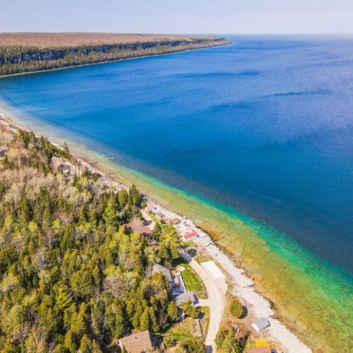 Breathtaking aerial perspective capturing the lush, dense greenery of the peninsula, contrasting beautifully with the vivid blue and green hues of the picturesque coastline that stretches far into the distance.