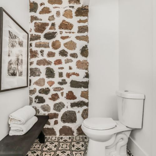Second bathroom with a stone feature wall and a handy bench for towels or toiletries.