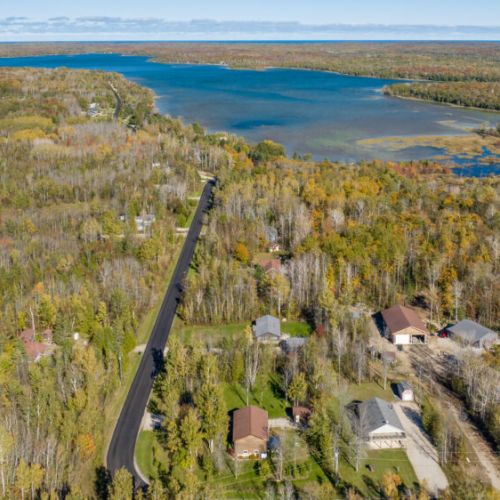 This expansive aerial shot captures the beautiful lake located near the property, offering guests the chance to enjoy water activities or scenic walks along the shore. The vibrant autumn colors of the trees add to the breathtaking natural surroundings.