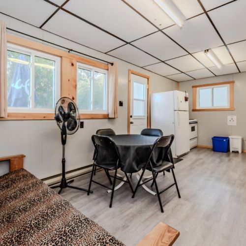 The living area features a futon and dining table, with a compact yet functional kitchen setup for all your needs.