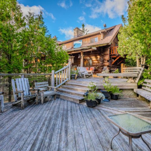 This expansive main deck, with comfortable seating and lush greenery, creates an ideal gathering space for outdoor meals, relaxation, or enjoying the tranquil surroundings.