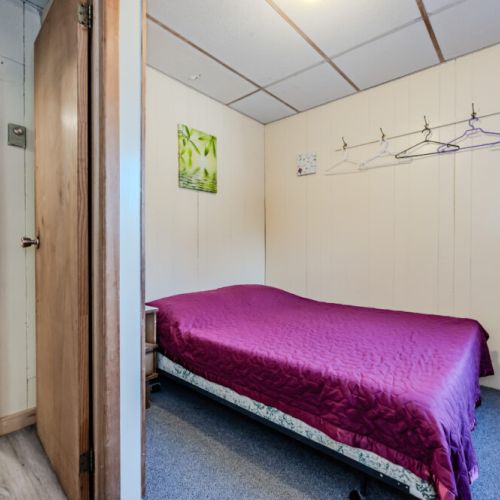 Another bedroom featuring a vibrant purple bedspread, adding a pop of color to the cozy cabin interior.