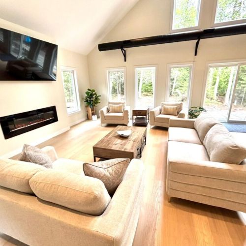 Bright, spacious, and designed for comfort – unwind in the open-concept living room featuring vaulted ceilings, a cozy fireplace, and large windows with serene forest views.