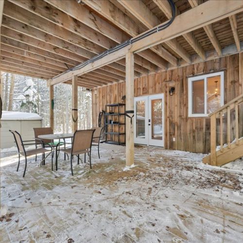 Covered patio space beneath the shared cabin with outdoor seating and easy access inside. Perfect for a sheltered hangout no matter the season.