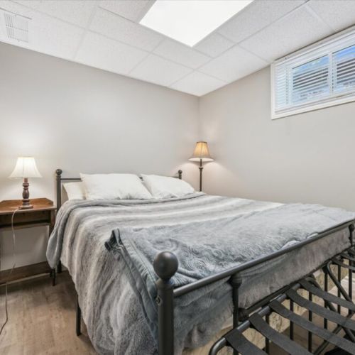 Cozy lower-level bedroom with soft lighting, plush bedding, and a peaceful atmosphere for restful nights.