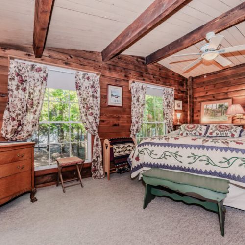 Wake up to forest views in this charming bedroom. Featuring cozy quilts, vintage furnishings, and natural light—perfect for peaceful mornings during your countryside retreat or family vacation.