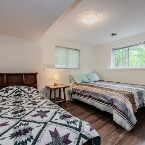 This charming bedroom offers a peaceful retreat with its soft lighting, comfortable beds, and cozy quilts, ensuring a restful night's sleep.