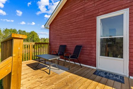 Relax on the spacious new deck with comfortable outdoor seating and peaceful views across the property.