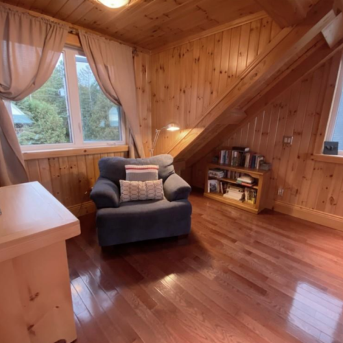 Relax with a good book in this peaceful reading corner, complete with a plush armchair and natural lighting from large windows.