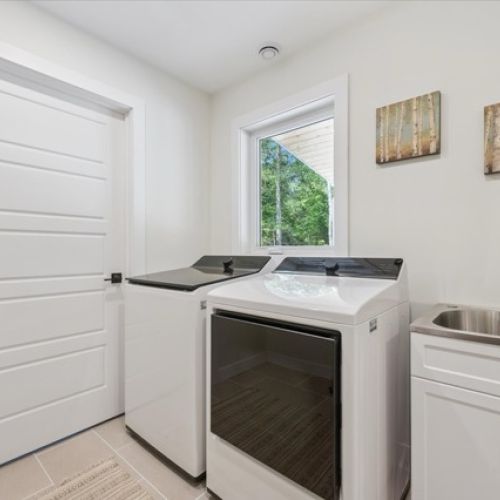 Bright and functional, this stylish laundry room features high-efficiency appliances, a deep utility sink, and a serene view to make chores a little more enjoyable.