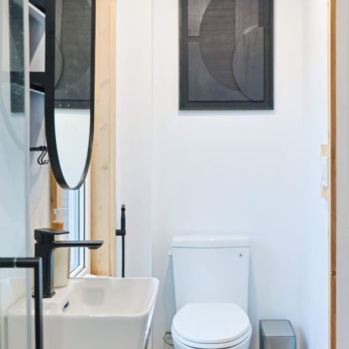 Sleek and Stylish: This modern bathroom features sleek black fixtures, a luxurious full-size standing shower, and a modern lighting system with sensors for added convenience.