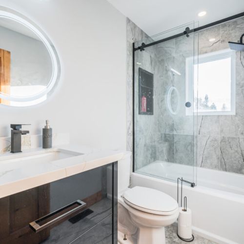 This bathroom offers clean lines and a marble finish for a refreshing and straightforward appeal. Bright mirrors and modern fittings create a practical and relaxed space to refresh and recharge.