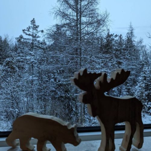 Charming wooden moose and bear figures overlook the snowy forest—bringing a touch of woodland whimsy to your winter retreat.