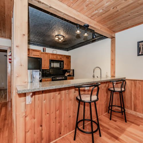 Enjoy casual dining at the breakfast bar in a wood-paneled cottage kitchen—ideal for morning coffee or laid-back cooking sessions.