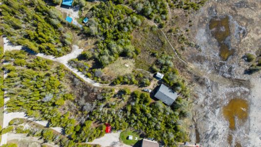 An aerial view showcasing the private cottage setting, surrounded by trees and just moments from the shoreline.
