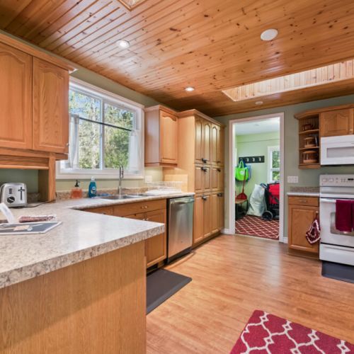 Bright kitchen workspace with lots of cabinets, a dishwasher, and an easy flow into the rest of the cottage.