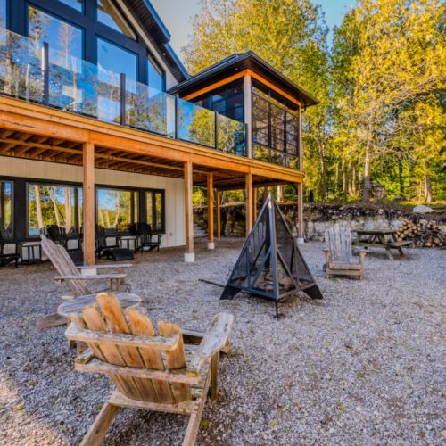 Relax and reconnect at this forest-side vacation rental featuring a fire pit lounge, glass-railed deck, and multiple seating areas—ideal for family gatherings, outdoor dining, and tranquil getaways in nature.