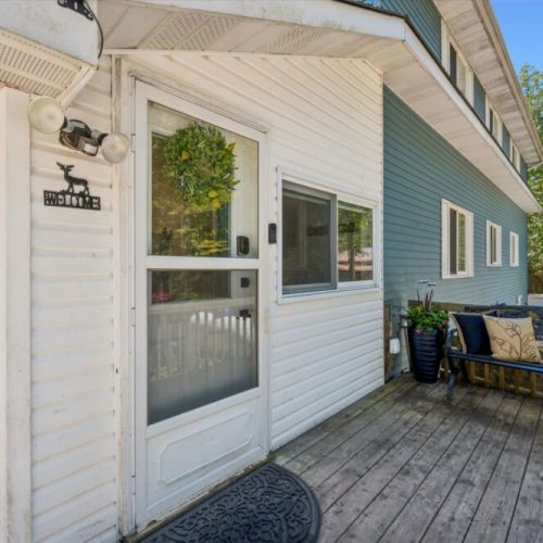 Welcoming cottage entrance with covered deck access and a cozy outdoor sitting area.