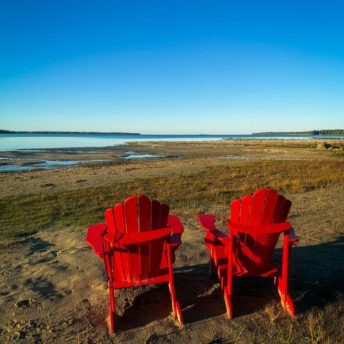 Iconic red chairs overlooking the calm waters of Lake Huron — the perfect spot for morning coffee or sunset views.
